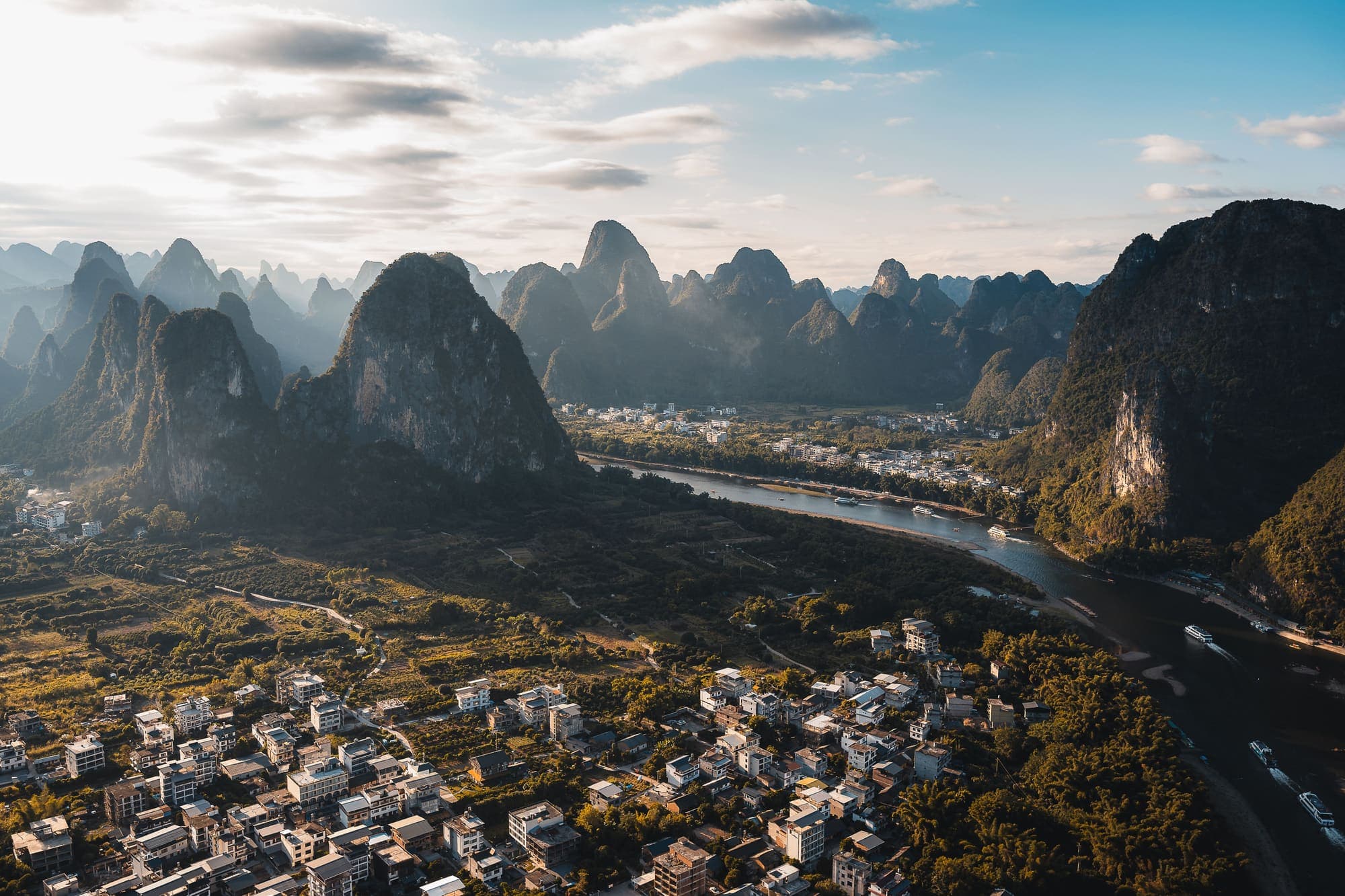 Vista aérea dos picos de calcário de Guilin, com o Rio Li passando entre eles e uma vila no vale.