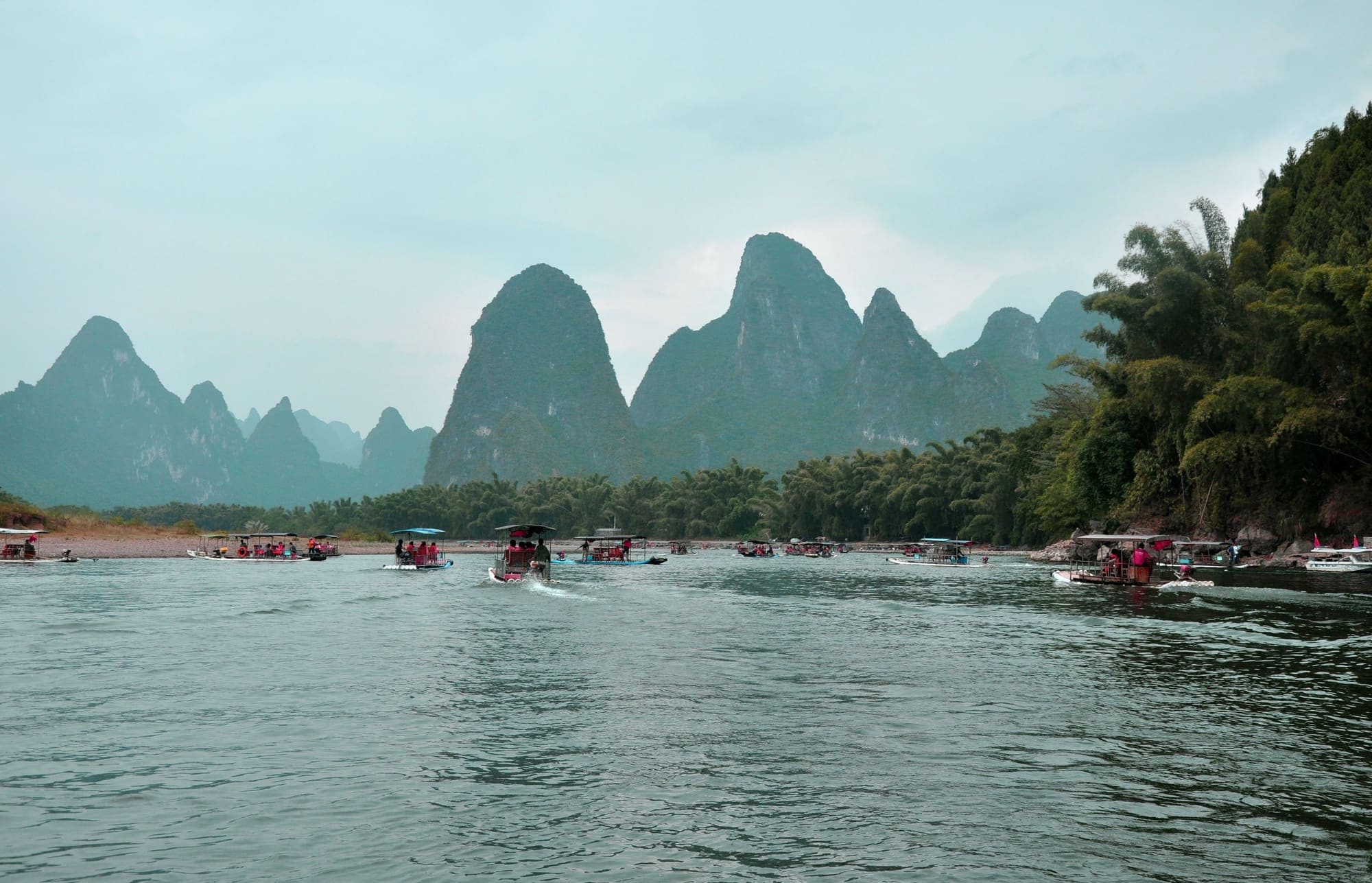 Barcos navegando pelo Rio Li, entre picos de calcário cobertos de vegetação.