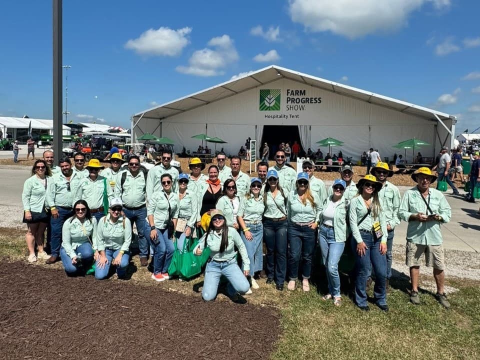 Grupo Duquima com camisas verde-claras em frente à tenda de hospitalidade da Farm Progress Show.