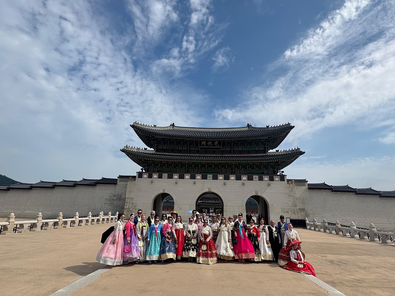 Grupo da Leão Viagens vestido com hanbok, a roupa tradicional coreana, diante do portão de um palácio.