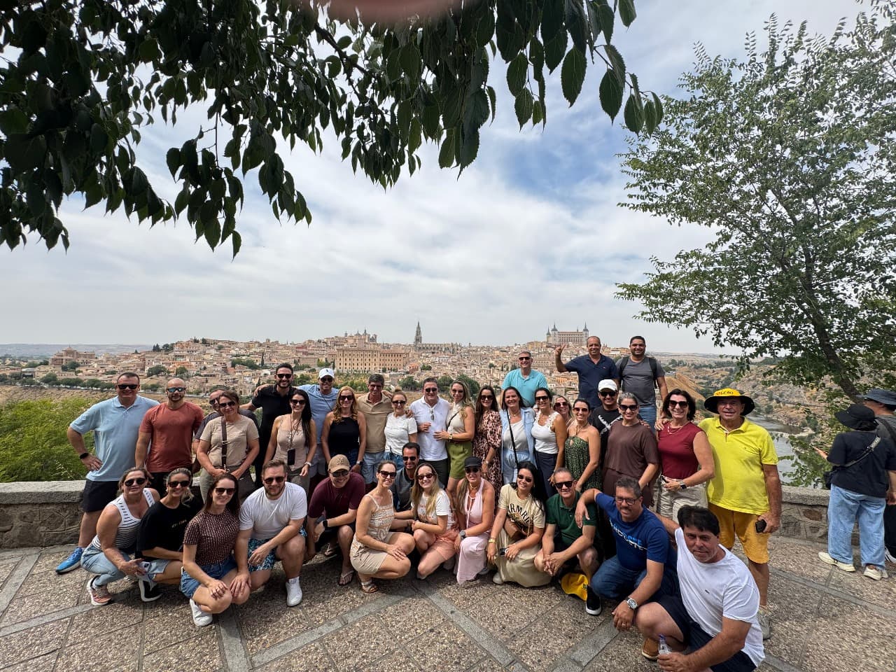 Grupo grande da Leão Viagens num mirante, com uma cidade antiga e sua catedral ao fundo.